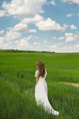 Fototapeta na wymiar Romantic beautiful bride on sunny summer day outdoors. Young blonde woman in a beautiful wedding dress is running across the field. Concept of wedding photoshoot in rustic style