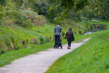 A family of a male and female couple and child in pushchair walking along a nature trail footpath...