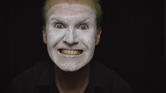 Clown Halloween man portrait. Close-up of an evil clowns face. White face makeup