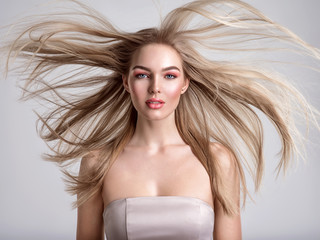 Portrait of a blonde beautiful woman with a long straight light hair. Flying hair.