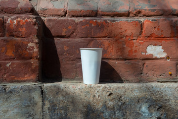 White Cup on a Red Brick Wall Background