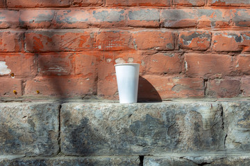 White Cup on a Red Brick Wall Background