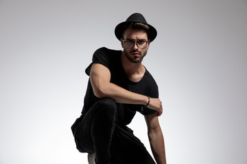casual man standing crouched with one hand resting on knee