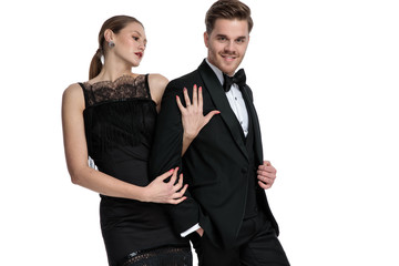 Beautiful girlfriend holding his boyfriend that is adjusting his jacket