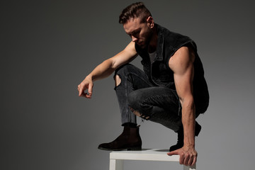 Handsome man squatting and getting off a chair