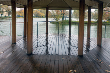 Wet wooden gazebo in the Park on a rainy autumn day overlooking the pond