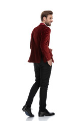 Fototapeta premium smiling groom wearing red velvet tuxedo and walking