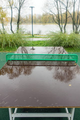 Wet ping pong table with reflection in the rain in the Park on a cloudy autumn day