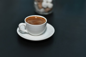 White cup of espresso coffee on a dark blurred background. Selective focus.