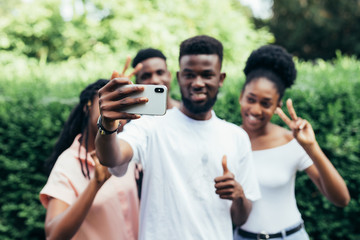 Group of students taking self-portrait with camera phone in campus.