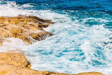 Blue emerald sea water with large stones beach. Rocky shore transparent turquoise bottom Malta