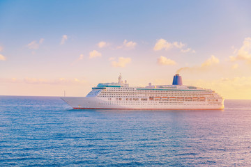 Fototapeta na wymiar Luxury cruise ship leaves port sunset in blue sea with clouds