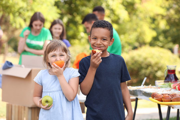 Poor little children with received food from volunteers outdoors