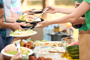 Young volunteers giving food to poor people outdoors