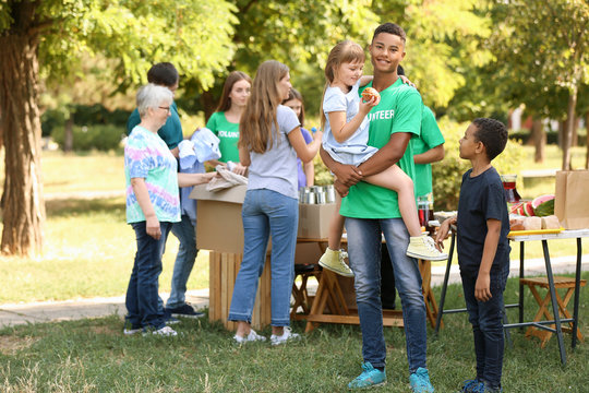 African-American volunteer with poor little children outdoors