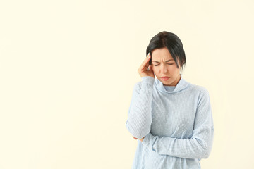 Portrait of woman suffering from headache on light background