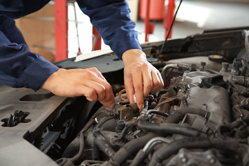 Male mechanic repairing car in service center
