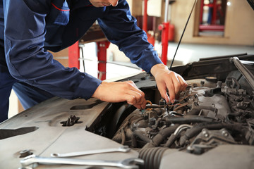 Male mechanic repairing car in service center