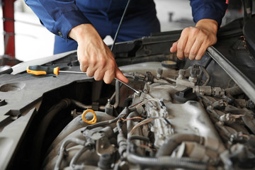 Male mechanic repairing car in service center
