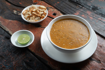 Traditional Turkish lentil soup with croutons and lime aside isolated on rustic wooden table