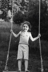 Black and white portrait of Cute little girl smiling on swing at summer day, Happy childhood concept.