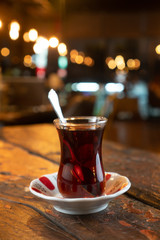 Glass of Turkish tea with spoon isolated on rustic wooden table