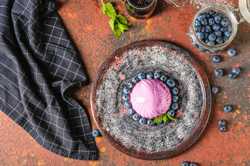 Plate with blueberry dessert on color background