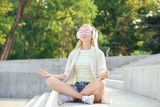 Beautiful young woman listening to music and meditating outdoors