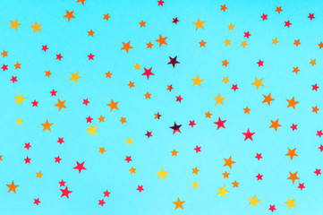 Celebration concept. Photo of multicolored stars sprinkles on blue backdrop. Festive holiday background for your projects. Christmas pattern. Top view, flat lay