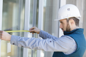 man measuring window prior to installation of roller shutter outdoors