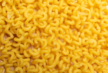 Raw yellow cavatappi pasta texture background top view