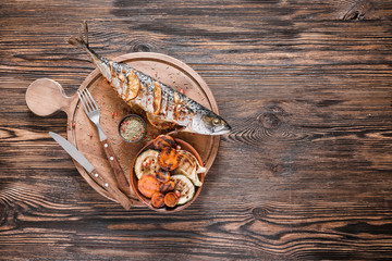 Board with prepared mackerel fish and vegetables on wooden background