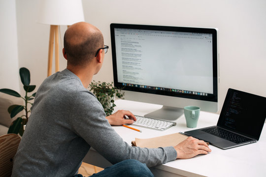 Programmer, working behind the desk, googling and coding at the same time