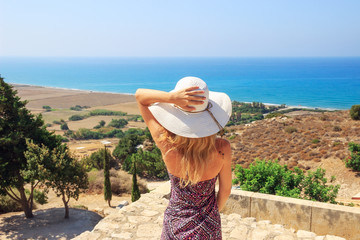 Portrait of beautiful woman wearing wide straw hat looking to the sea side