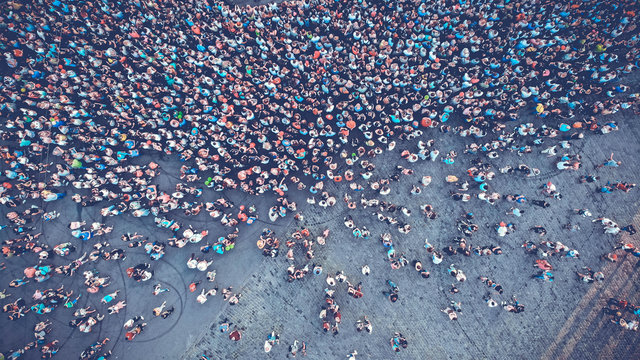 Aerial. People crowd on a city square. Mass gathering of many people in one place. Top view from drone fly. Toned image.