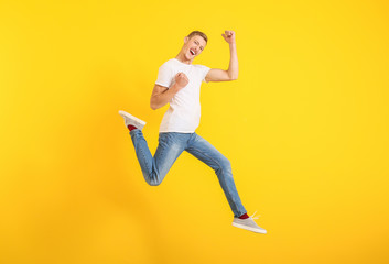 Fototapeta na wymiar Jumping man in stylish t-shirt on color background