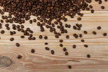 Dark brown whole coffee beans on wood background with copyspace