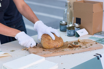Close up of hands slicing bread for tasting at outdoor market place.
