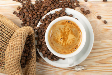 Hot coffee cup and coffee beans on brown background top view