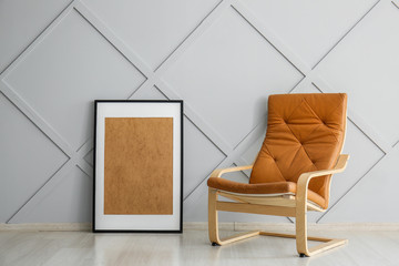 Stylish armchair with photo frame near grey wall in room