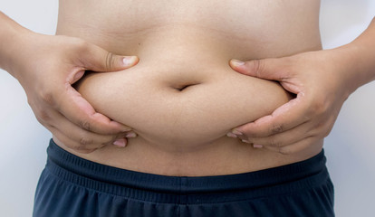 Naklejka premium Overweight Asian obese men, He is feeling ill and worried about his excess weight. He squeezed his belly, showing the excess fat that was isolated on a white background