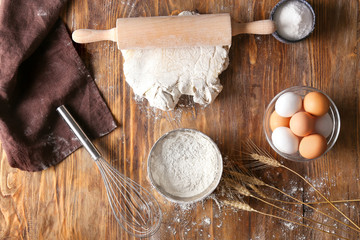 Dough with fresh products on wooden background