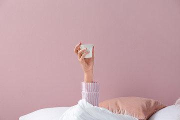 Young woman with cup of coffee lying in bed