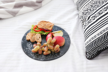 Tray with tasty breakfast on bed