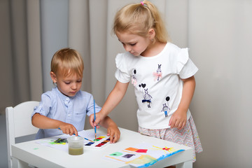 Brother and sister, girl and boy paint with watercolors at the t