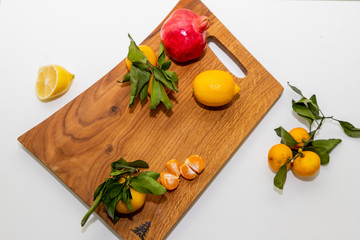 Group of various fruit consists half of tangerines, pomegranates,lemon close up fresh fruit on wooden cutting board, vitamin c from fruit.Organic tropical fruits