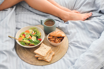Woman with tasty breakfast sitting in bed