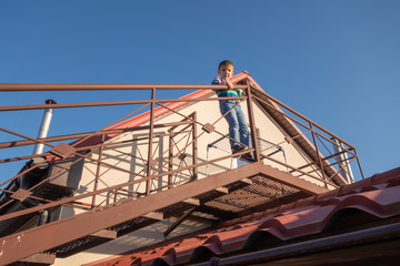 Naklejka premium A large metal staircase outside the building. The child climbed out onto the staircase railing. Danger.