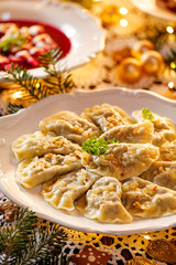 Christmas dumplings stuffed with mushroom and cabbage on a white plate on a holiday table,...