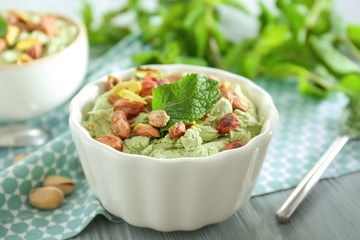 Bowl with tasty pistachio ice cream on wooden table